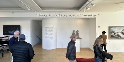 A sign above the gallery wall reads Sorry for killing most of humanity