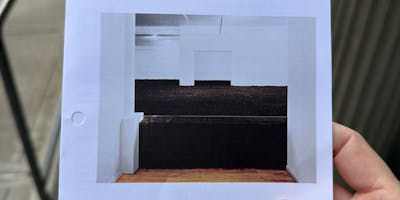 Photo of a flyer showing a photograph of the Earth Room - a glass wall about two feet high holds back a large file of dirt in a white room.