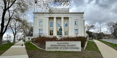A grand building with Pioneer Memorial Museum written in gold letters along the top, and a plaque in front of it reading Headquarters International Society Daughters of Utah Pioneers