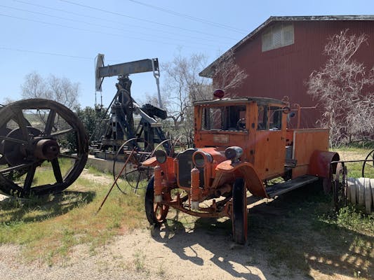 An old truck and some historic oil equipment.